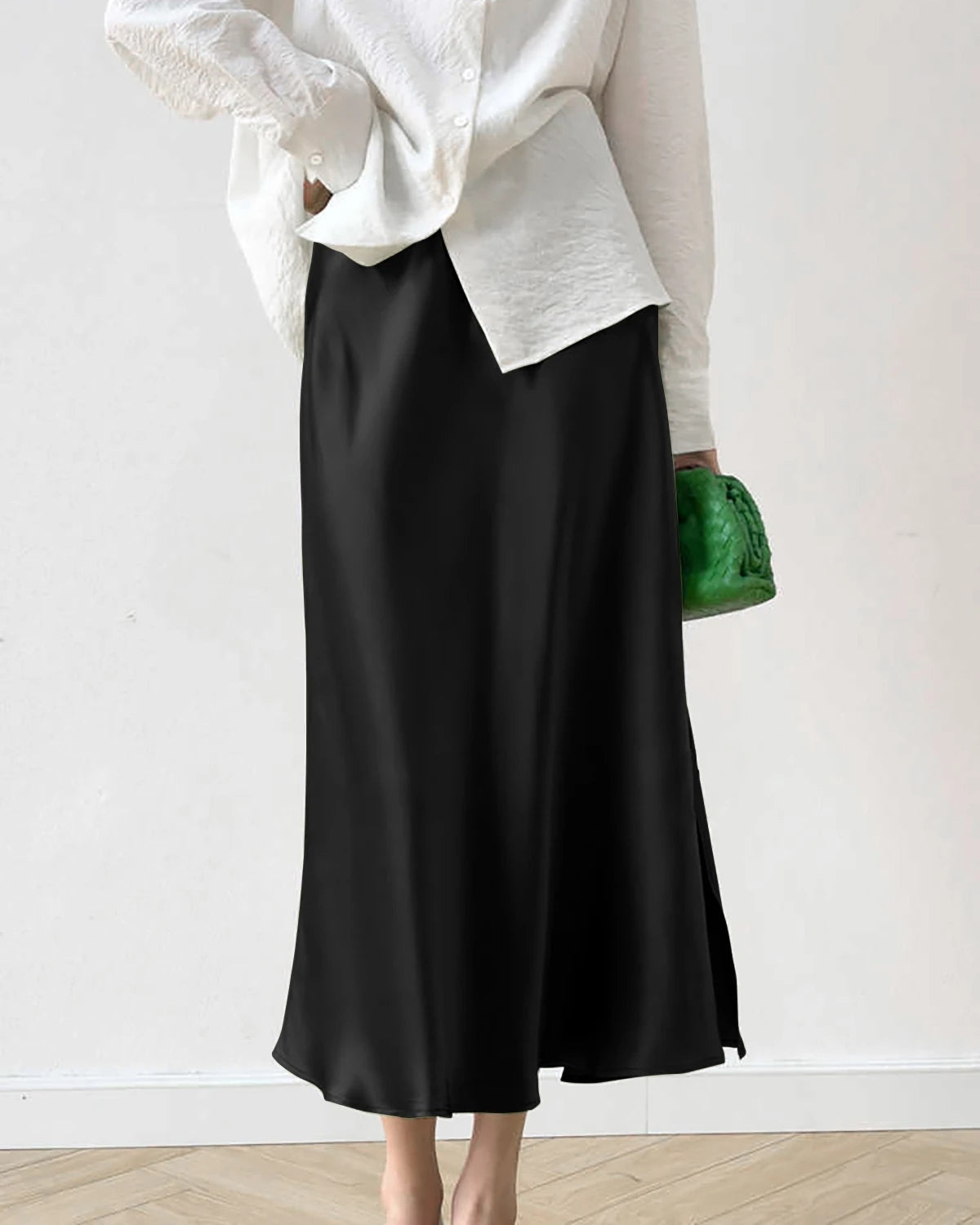 A person wearing a high-waist midi skirt with a side slit, in a black hue.